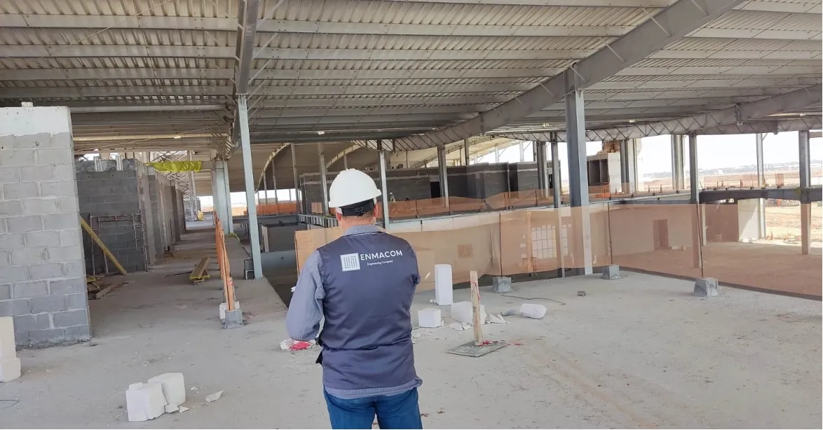 EnmaCom engineer on a construction site under a steel roof structure