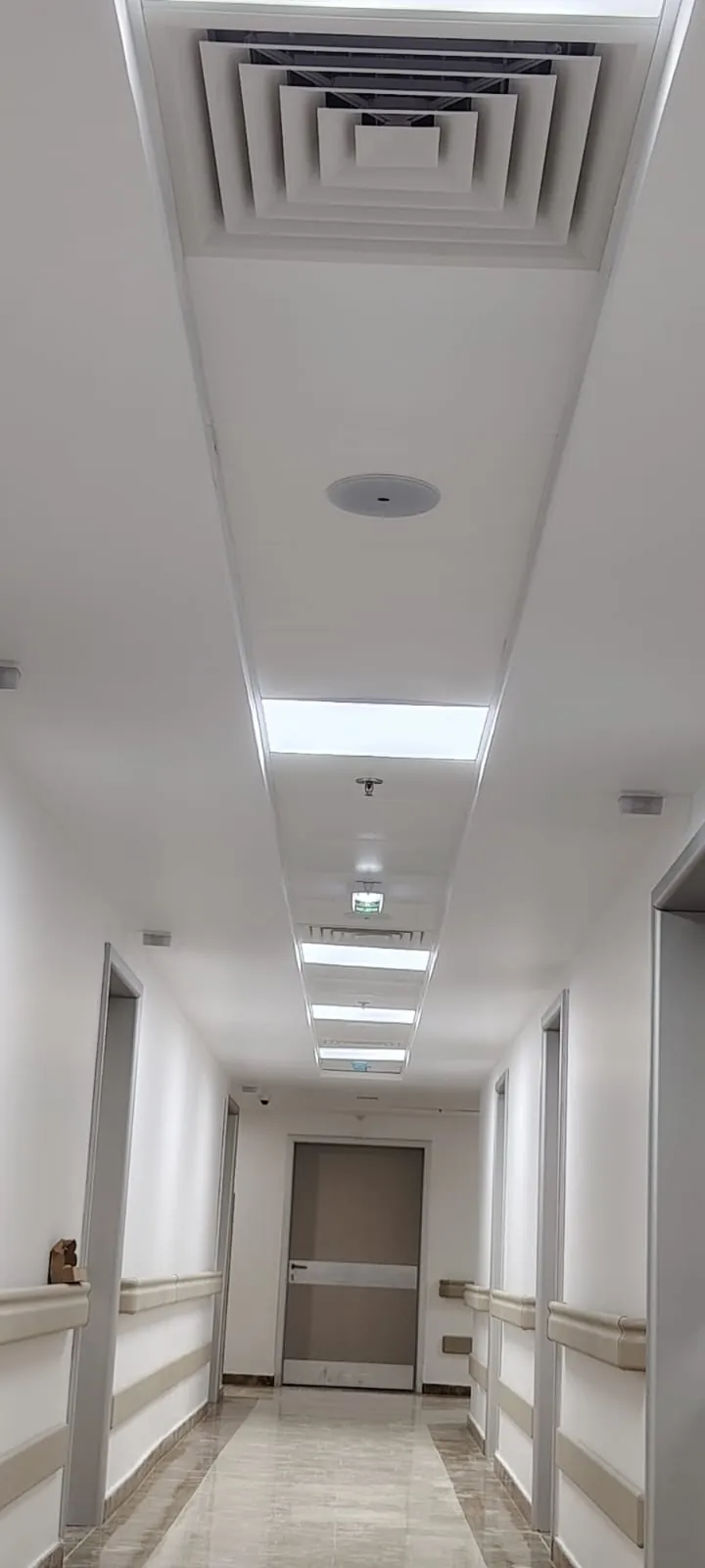 Finished hospital corridor with ceiling air diffusers, lighting, sprinklers and smoke detectors