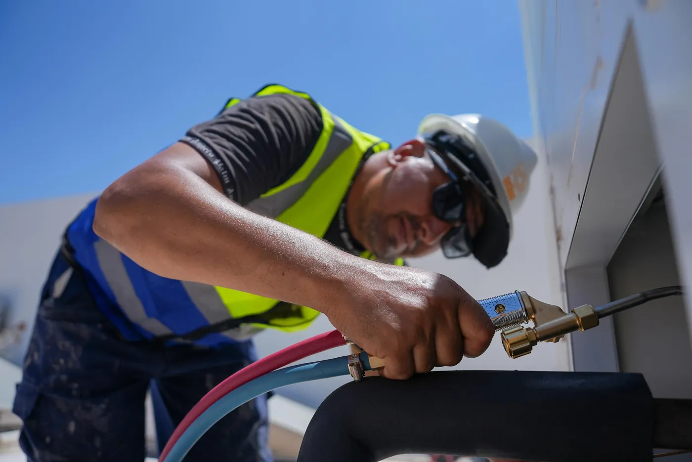 HVAC technician connecting service hoses to an outdoor unit